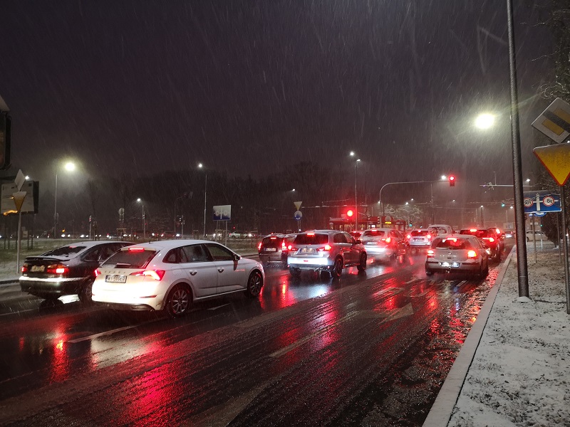 samochody oczekujące przed skrzyżowaniem na czerwonym świetle; opady deszczu i śniegu