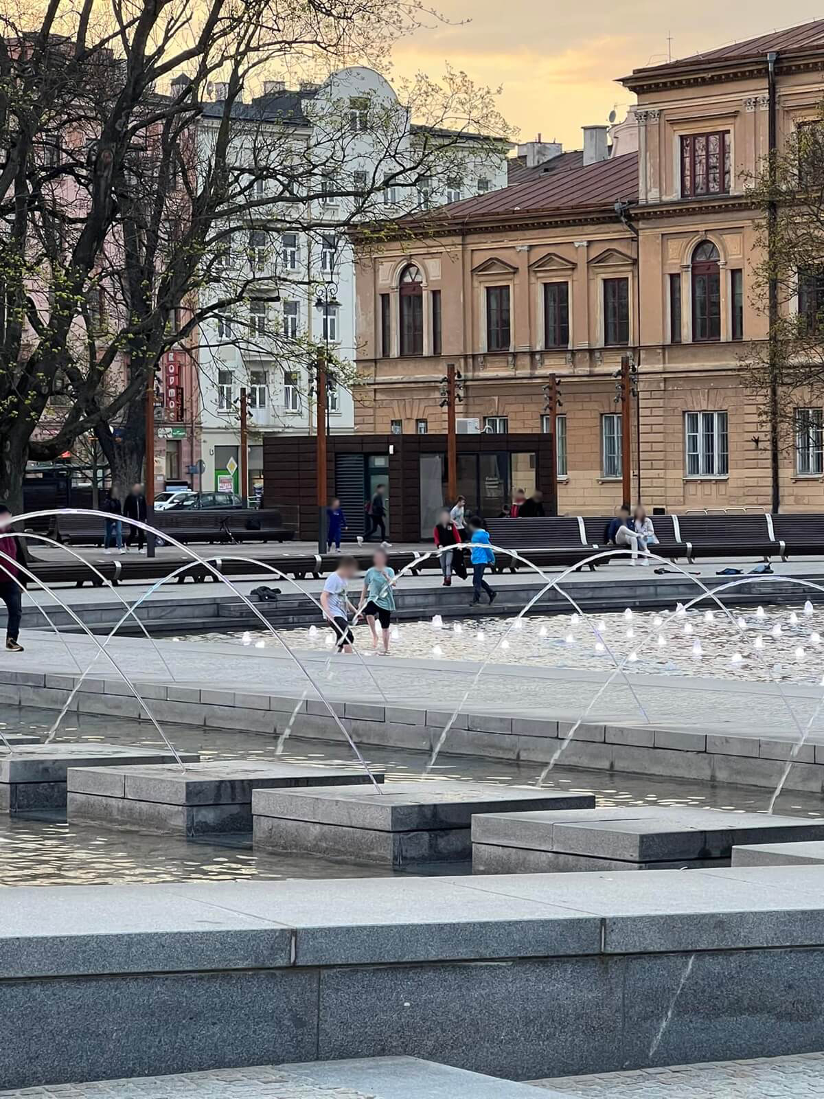 Dzieci biegające pomiędzy strumieniami wody w fontannie na Placu Litewskim