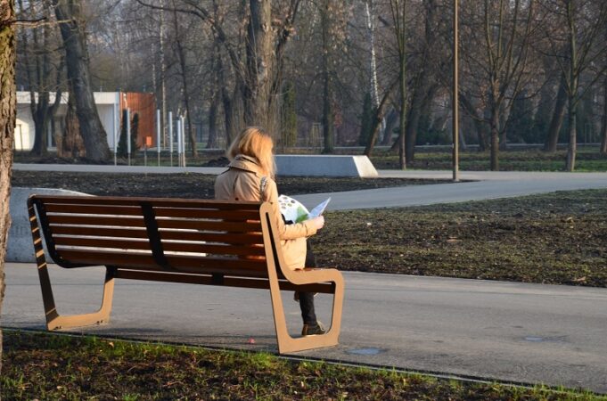 Kobieta czytająca gazetę na ławce w Parku Ludowym