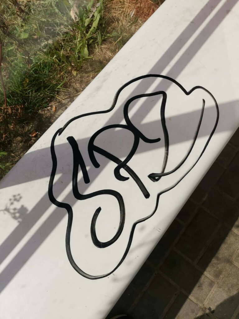napis graffiti na lawce wiaty przystankowej