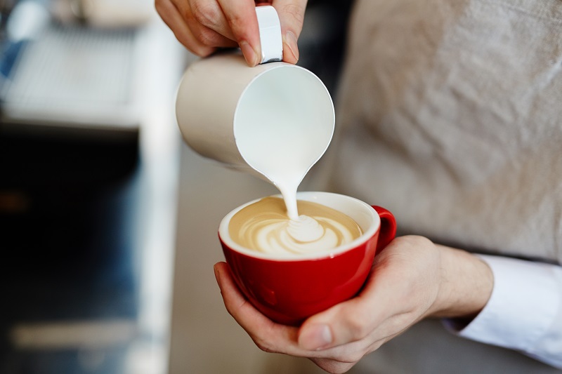 Barista dekorujący cappuccino mlekiem
