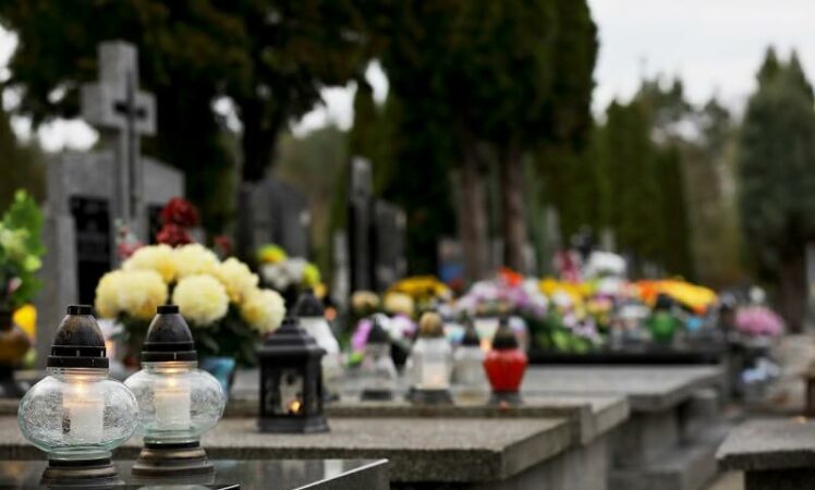 bukiet kwiatów w wazonie na cmentarzu, znicze na grobie