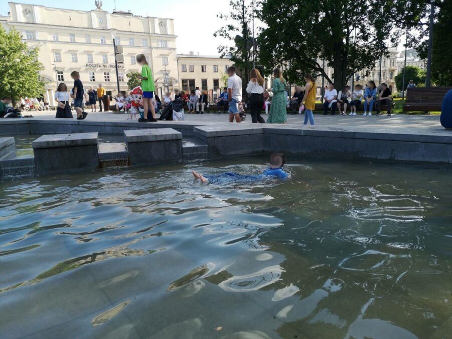 Dziecko pływające w miejskiej fontannie na placu Litewskim