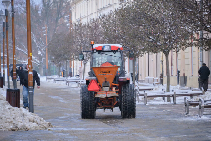 Opłużony ciągnik posypujący piasek na deptaku w Lublinie