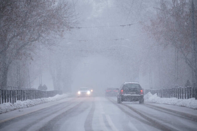 opady intensywnego śniegu, a w tle jadące samochody