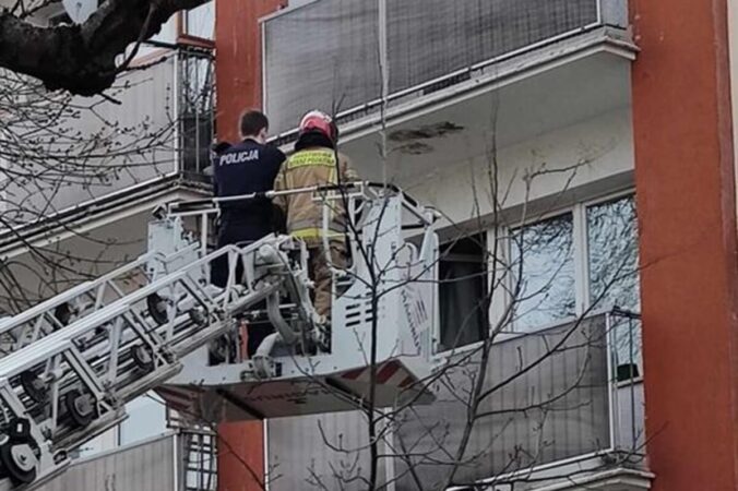 Strażak i policjant próbują wejść do zamkniętego mieszkania przez balkon