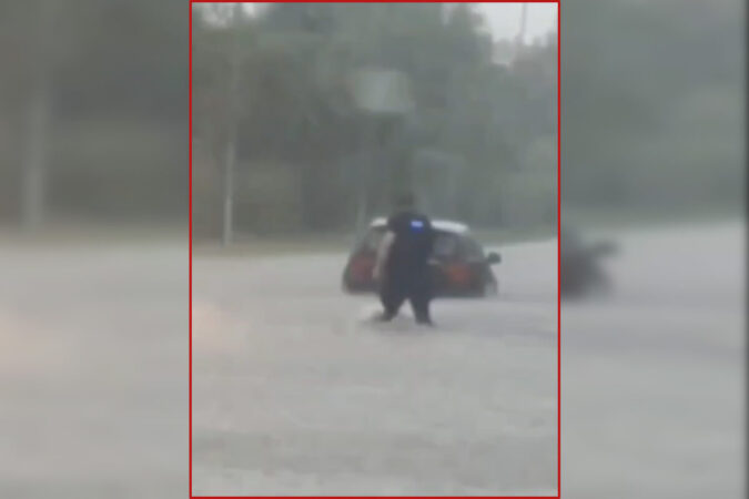 Policjant ratuje kobietę z auta na drodze