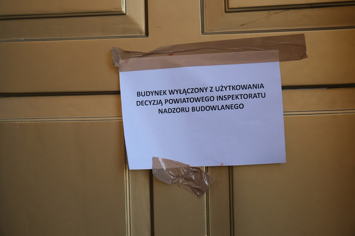 Kartka z informacją o wyłączeniu kamienicy z użytkowania na drzwiach do restauracji Św. Michał