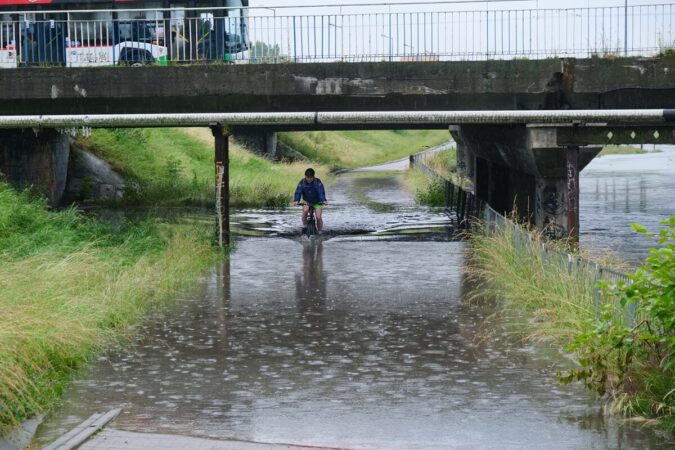 Rowerzysta jadący po zalanej ścieżce rowerowej przy ul. Mełgiewskiej