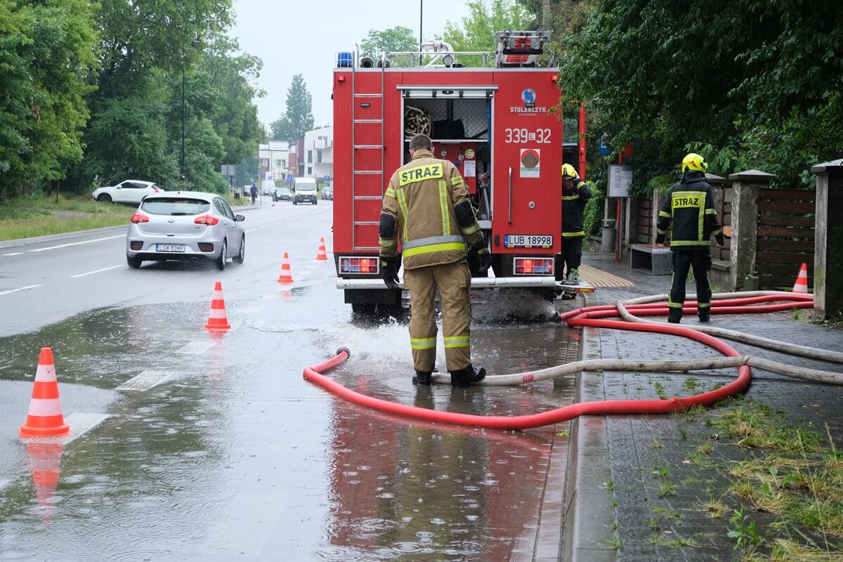 Strażacy wypompowujący wodę z zalanej posesji