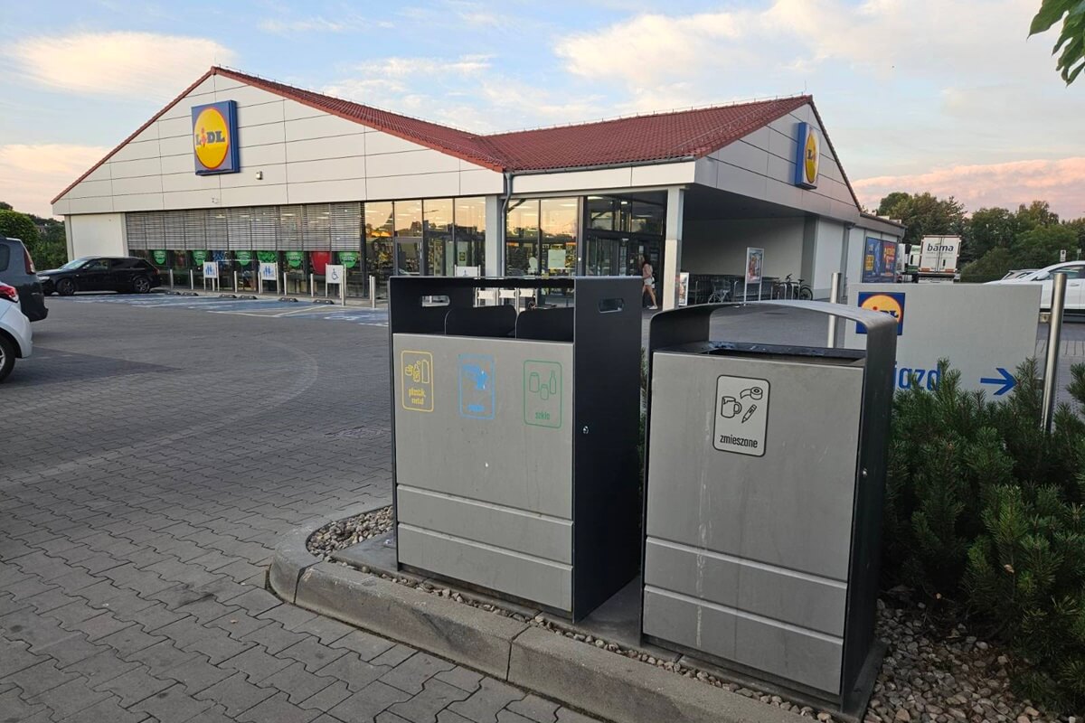 Kosze na śmieci ustawione przy wyjeździe z parkingu sklepu Lidl