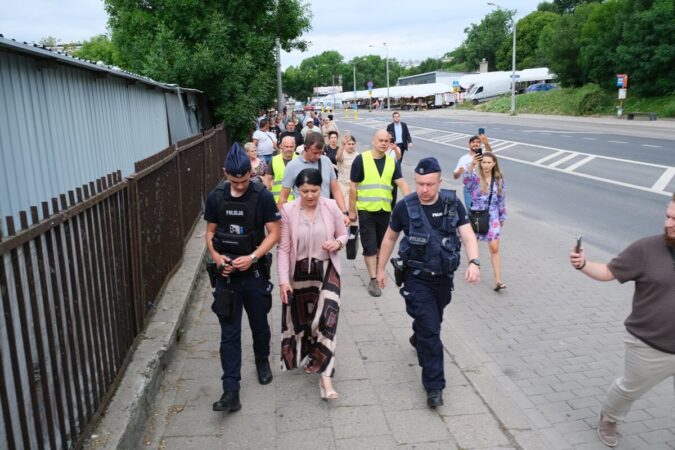 Prezes Lubelskich Dworców Anna Kusiak w asyście policji i idący za nimi handlarze z targowiska przy ul. Ruskiej