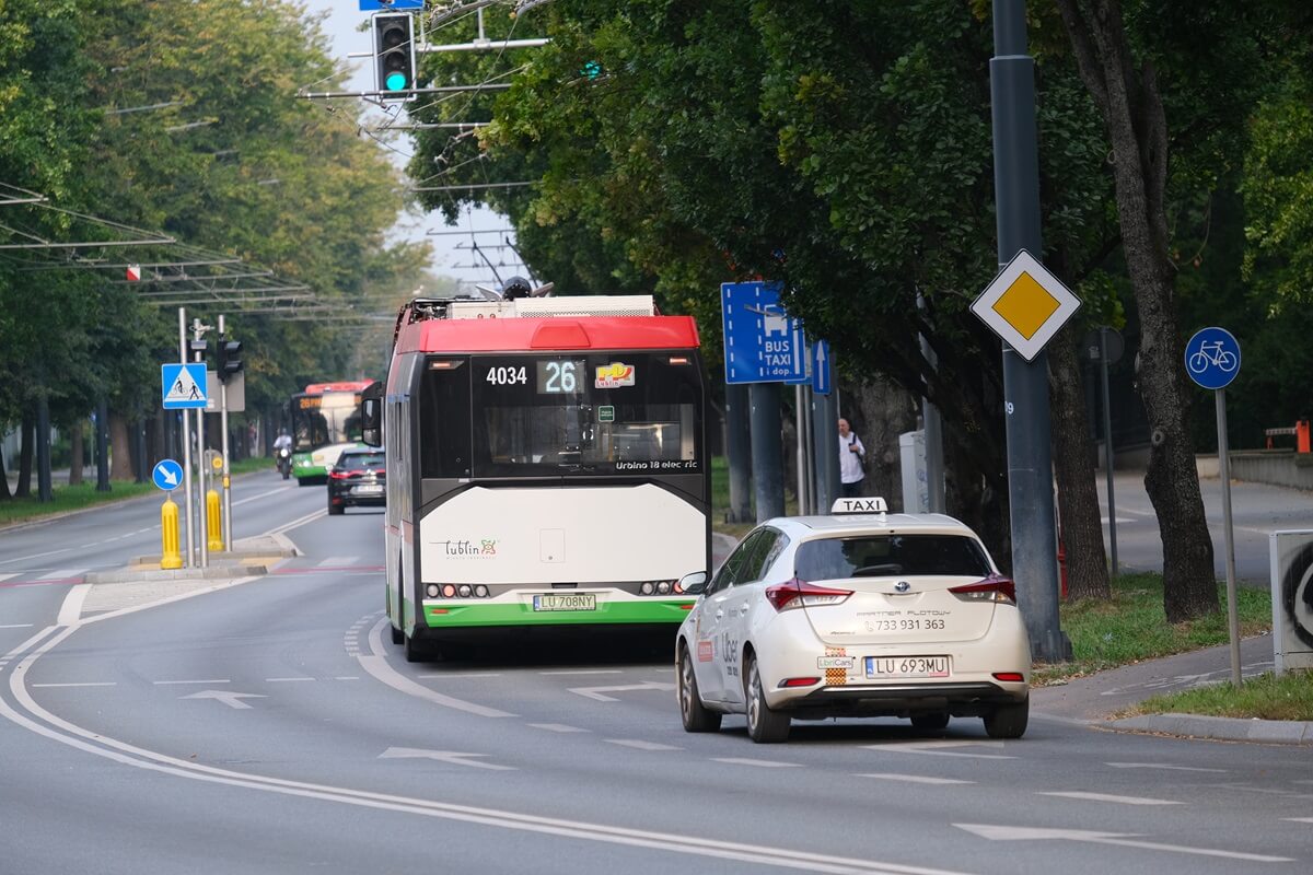 Autobus i taksówka jadące po buspasie